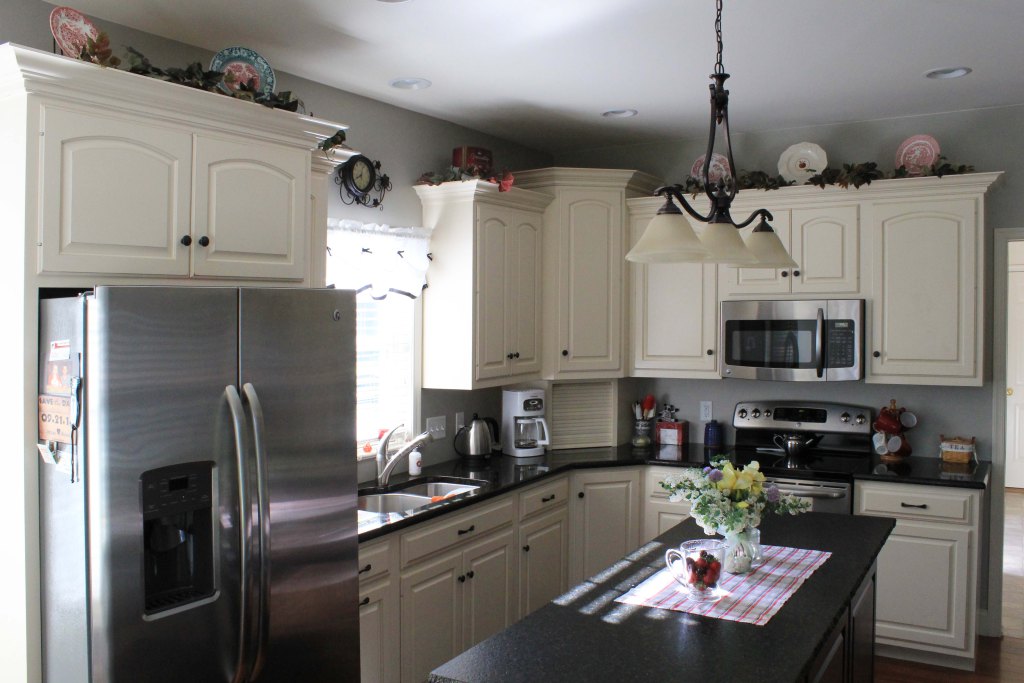 Gorgeous kitchen with white cabinetry, stainless steel appliances, black counters, center island