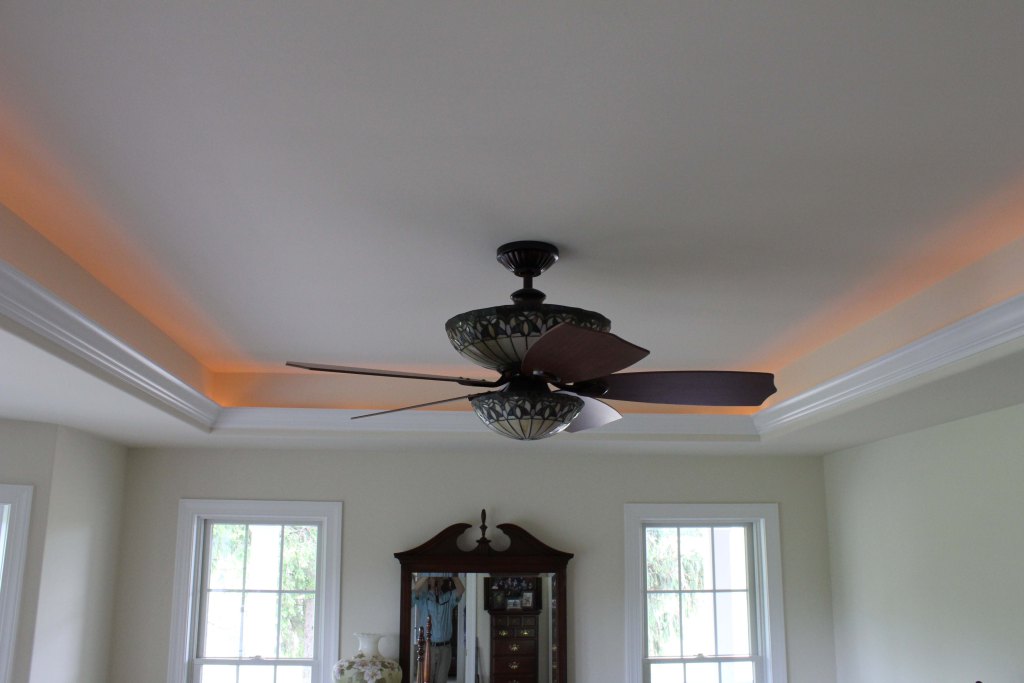 Lighted tray ceiling with uplighting and decorative ceiling fan featuring stained glass light feature