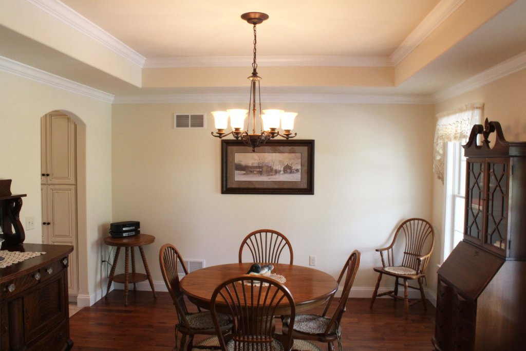 Dining room with deep tray ceiling, hardwood floor, arched opening to kitchen