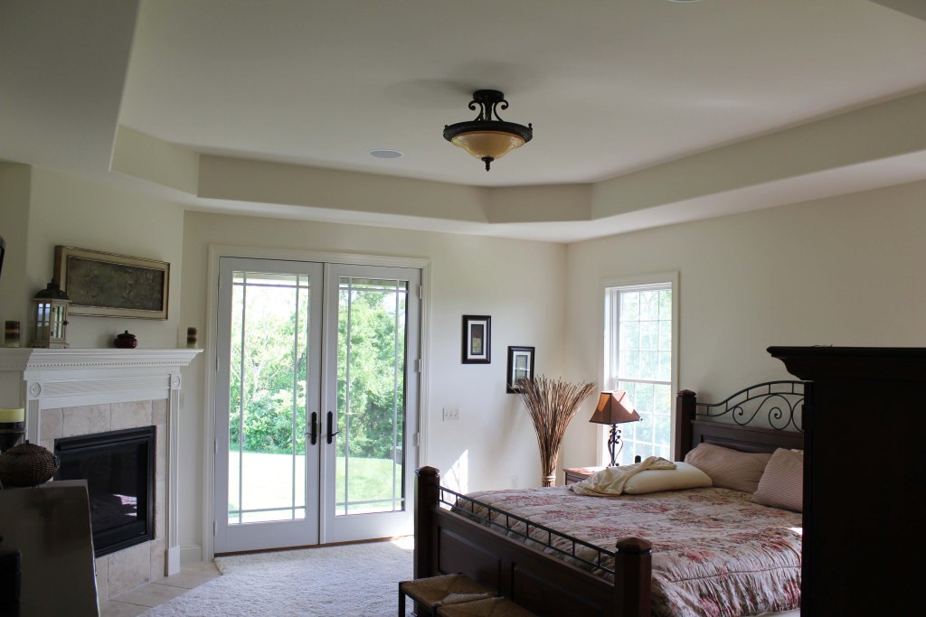 bedroom with tray ceiling, gas fireplace, and French doors