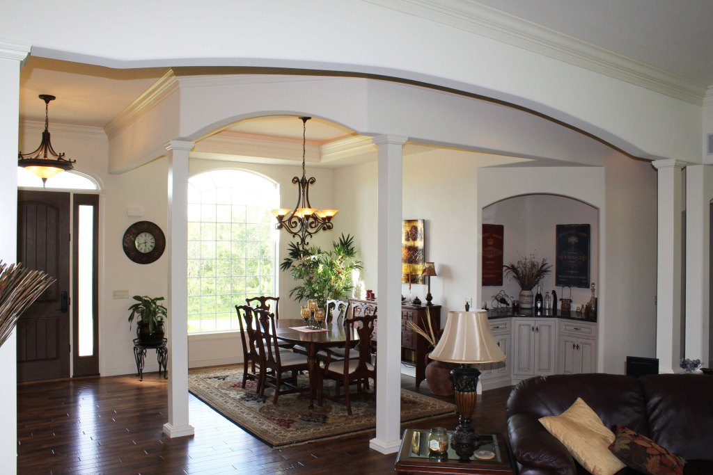 open dining room design with interior columns, open to foyer and family room, hardwood floor, arched openings, arched windows