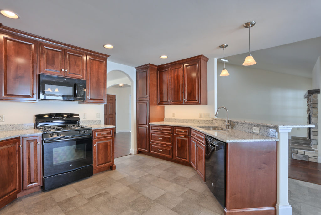 Kitchen remodeled with cherry cabinetry and hard surface countertops, open to family room